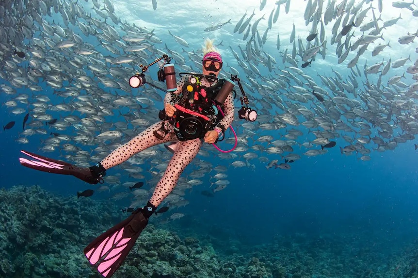 A woman swims with fish in the background