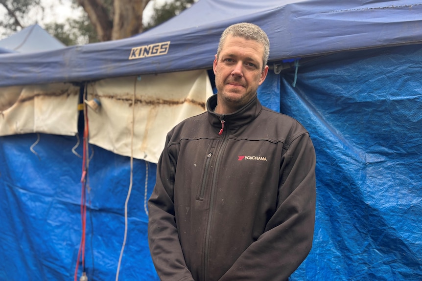 Man in fleece jumper standing in front of a tent