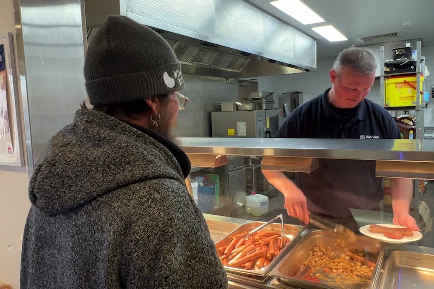 Man serves up breakfast to anothe rman from a bae marie