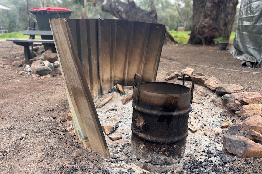 Burnt out camp fire bordered with corrugated iron and rocks