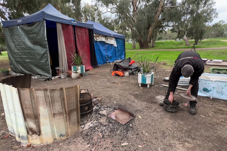 Man checks his camp overn pot as he cleans up his camp site