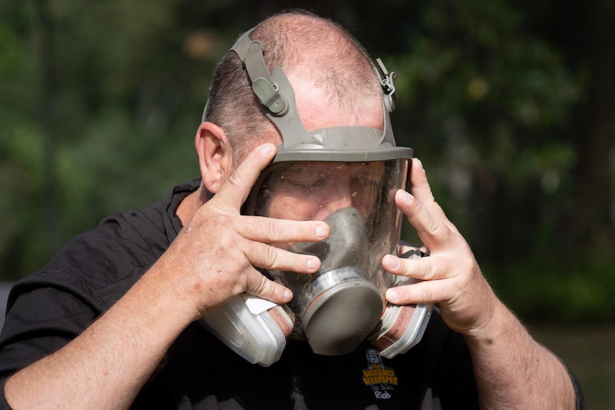 A man places on a gas mask