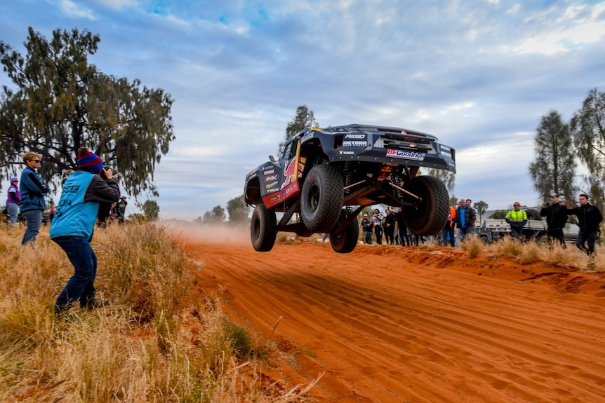 A car is launched into the air along a red desert track