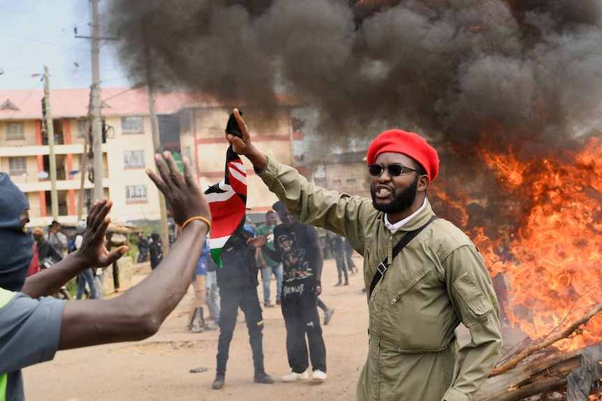 Protesters in the street with a fire blazing in the background.