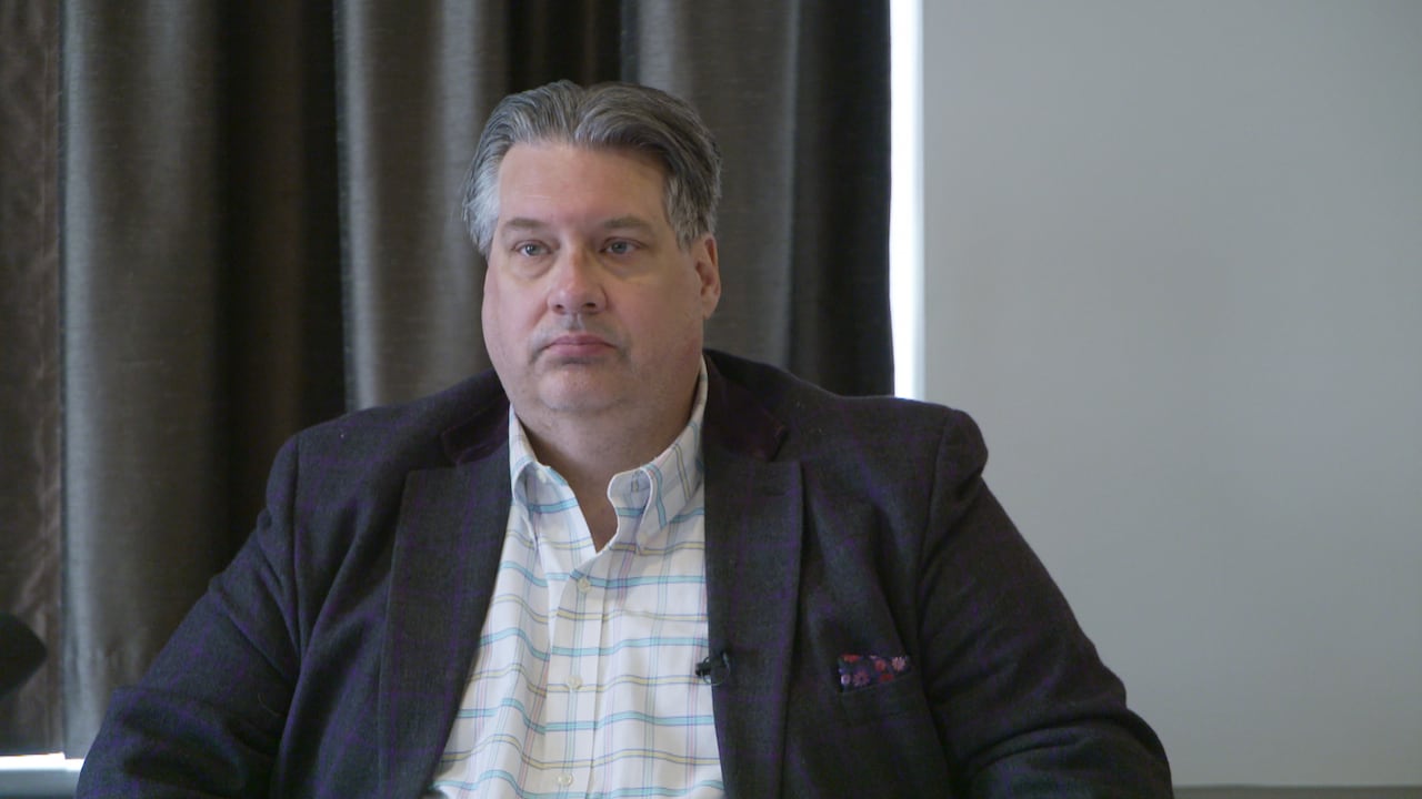 An unimpressed looking man in a blazer at a table.