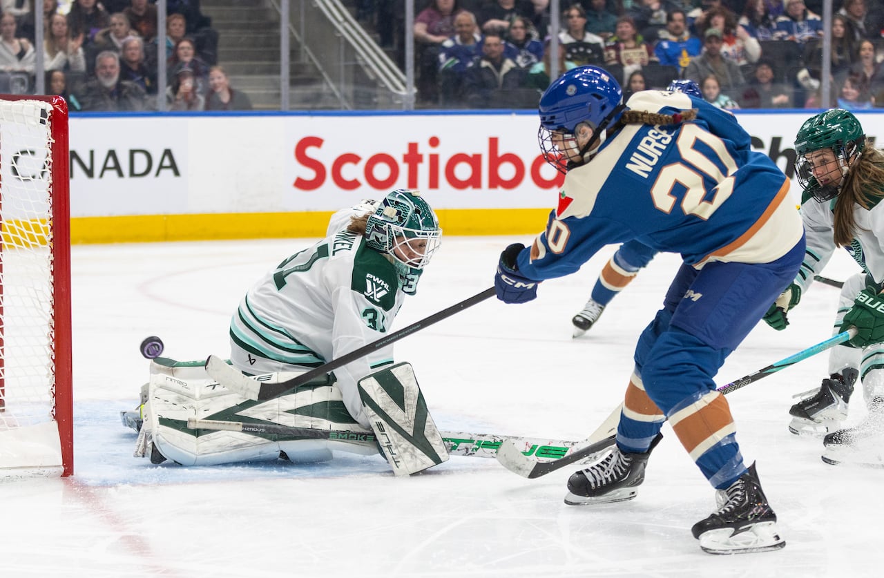 A goaltender makes a save on a player during a hockey game.