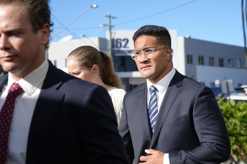broad man in a navy suit with glasses, woman next to him