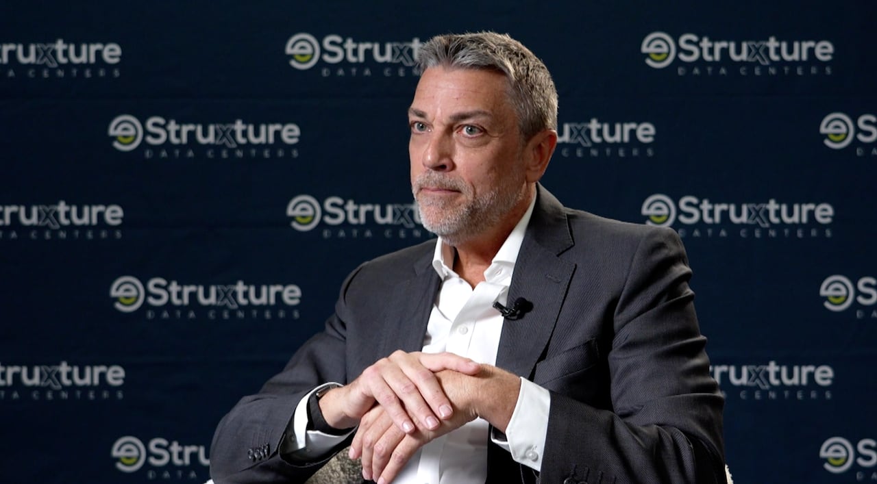 A businessperson in a suit is interviewed by a journalist.