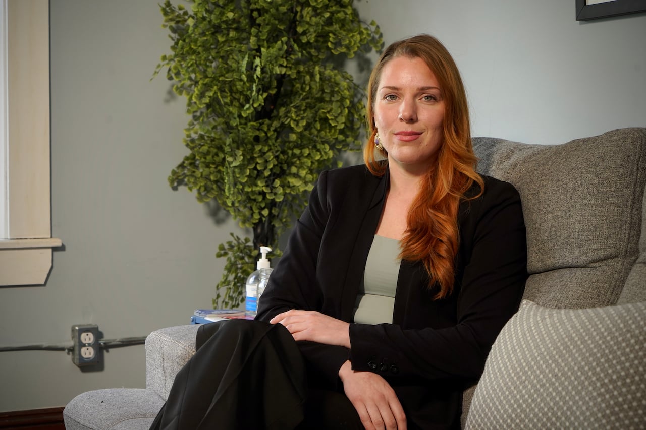 woman in a suit poses on a couch