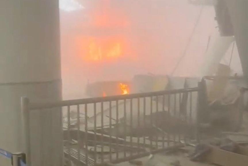 A fire blazes inside a damaged building.