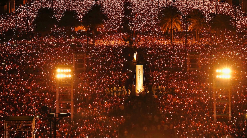 Tens of thousands of people hold candles at night in Hong Kong's Victoria Park.