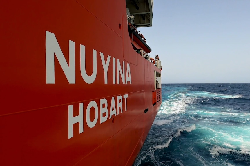 Close up side view of ship's name and ocean water out at sea