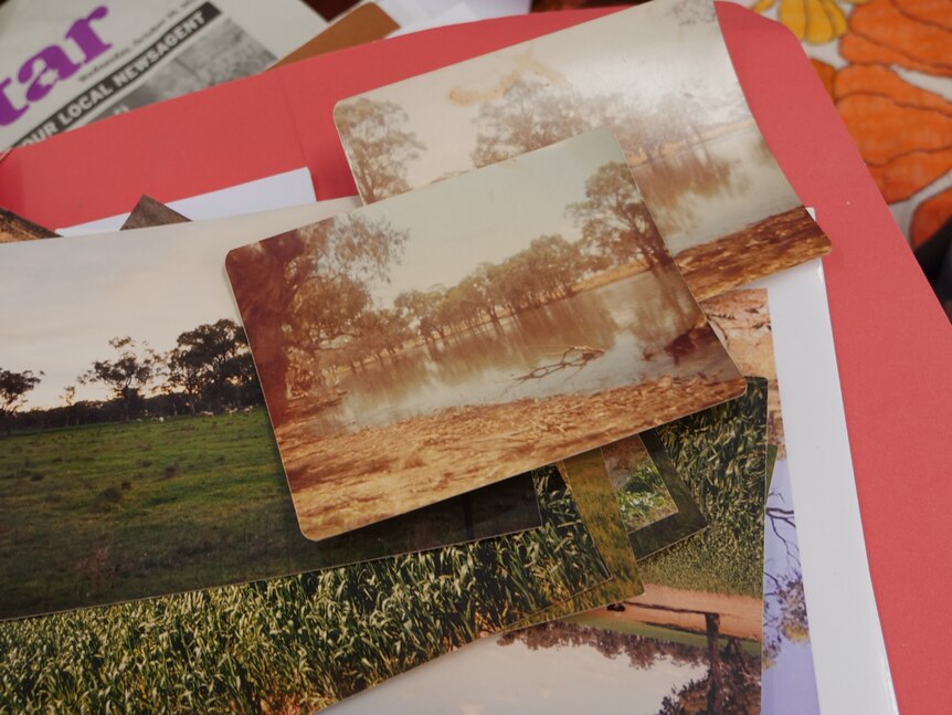 A stack of old photographs showing water in a river system and green crops.