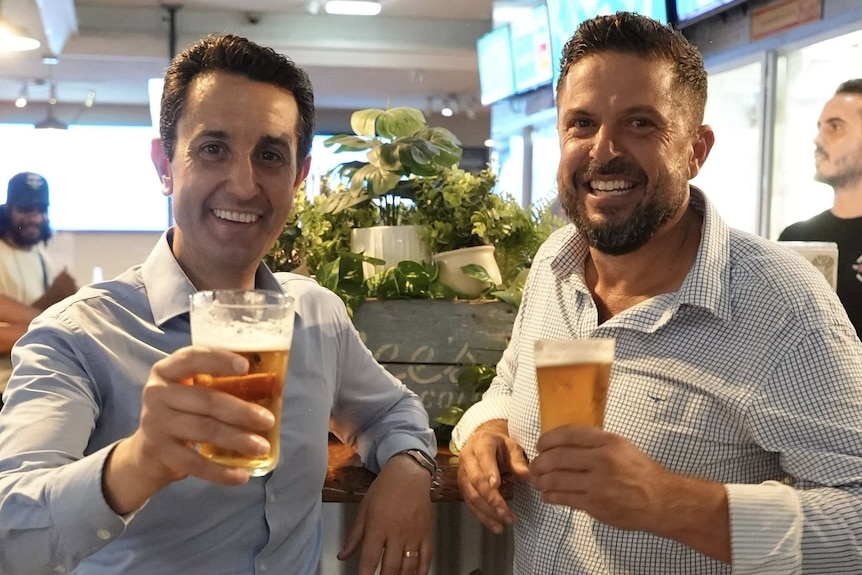 Two men in their 40's holding beer.