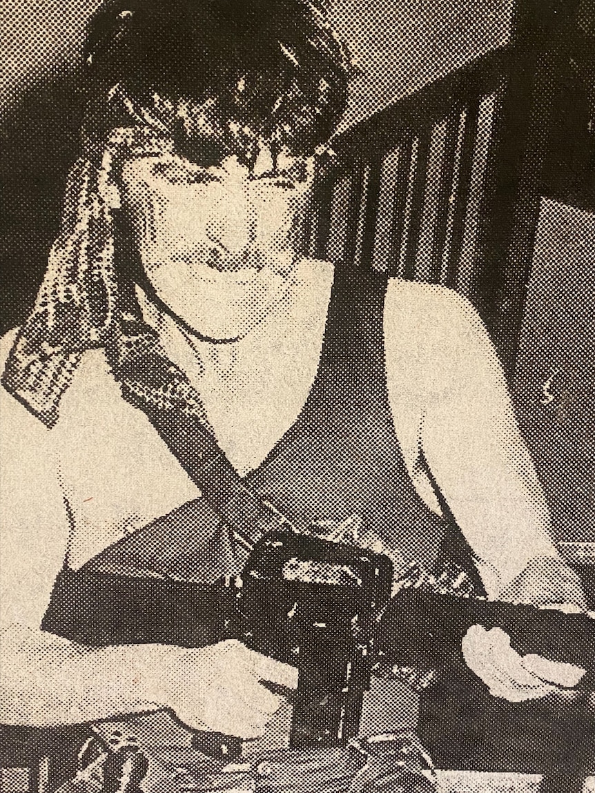 A black and white photograph of a man dressed up as Rambo, posing with a gun