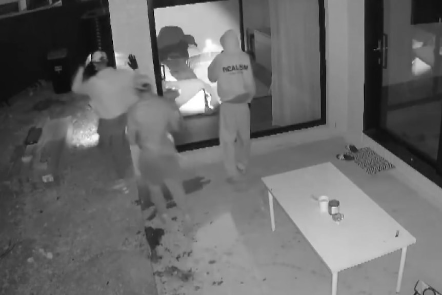a screenshot of cctv showing three people outside a home in black and white 