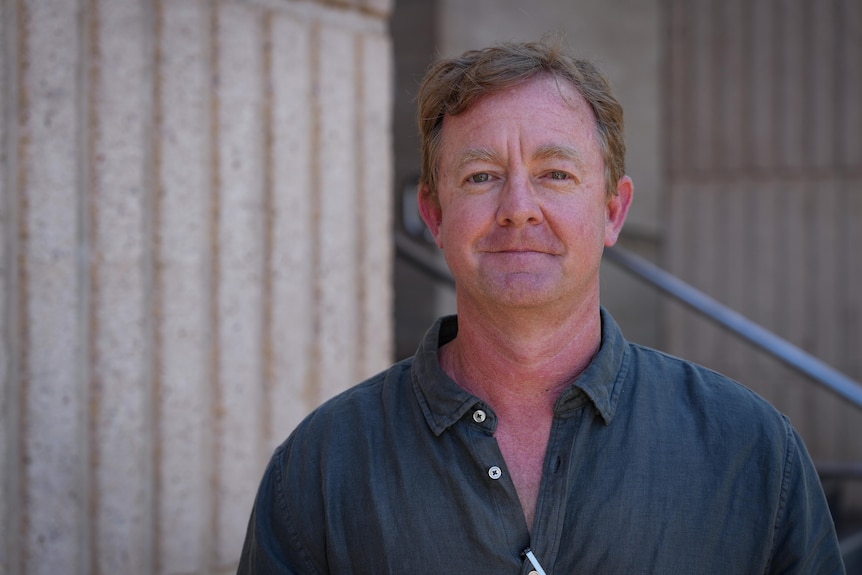 A man in a collared shirt offers a slight smile for the camera