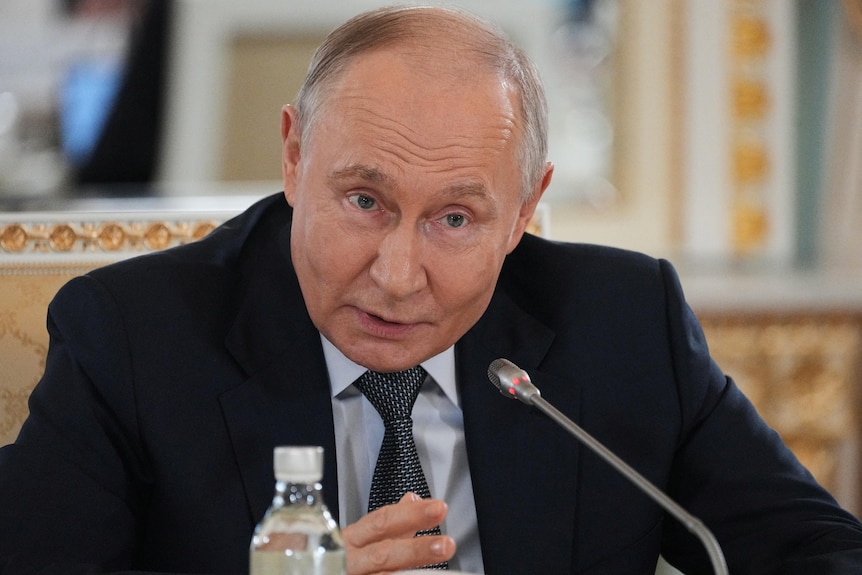 Russian President Vladimir Putin speaks into a microphone during a press briefing