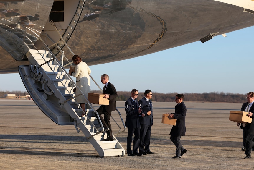 People carry cardboard document boxes up stairs to Air Force One.
