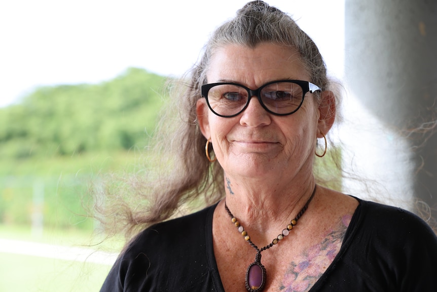 A woman in glasses and dark shirt smiling at the camera.