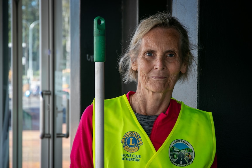 Woman in yellow high-vis vest holding a broom